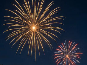 Fireworks exploding over a residential neighborhood in Wisconsin on July 4th, showing rooftops directly beneath the display.