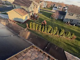 Rooftop solar array on a brown architectural asphalt shingle roof in a Wisconsin neighborhood