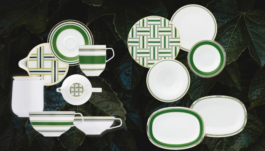 White and green dinnerware set with geometric patterns displayed against dark green leaves. Plates, cups, and saucers with stripes. Elegant mood.