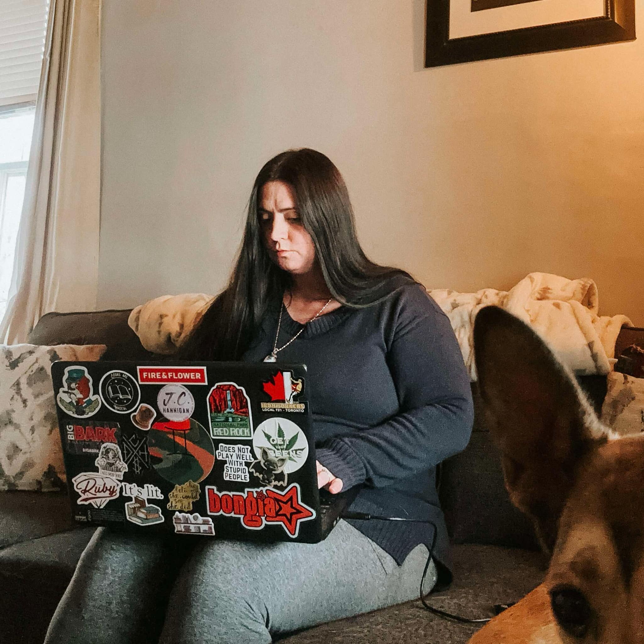 J.C. Hannigan writing on the couch with her dog.