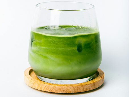 a glass of matcha with plant-based milk on a wooden coaster
