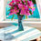 Thumbnail: Luxury art glass vase with a sculptural twisted shape holding bright pink flowers in natural sunlight