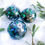 Thumbnail: This green, teal and gold set of 3 glass baubles are hand painted in shades of green, teal and gold accents