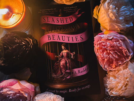 A book Slashed Beauties places on material with fake flowers and candles around it.