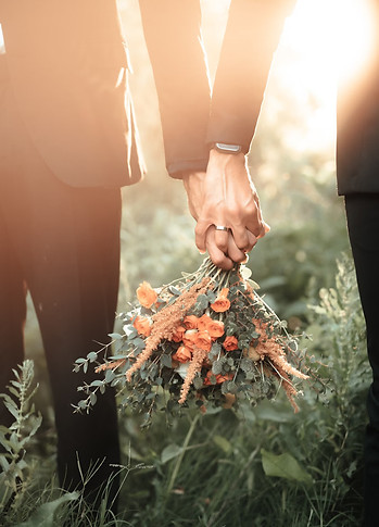 Two hands link together holding a flower bouquet
