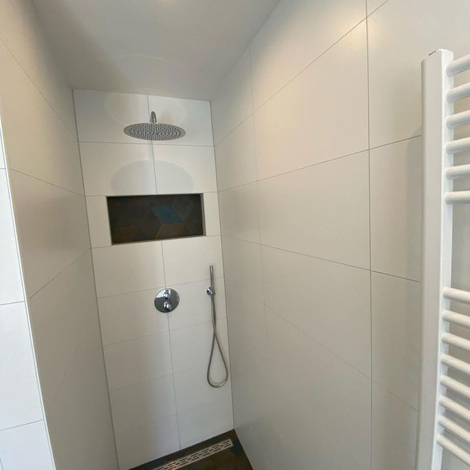 De vloertegel zit ook achter in de nis