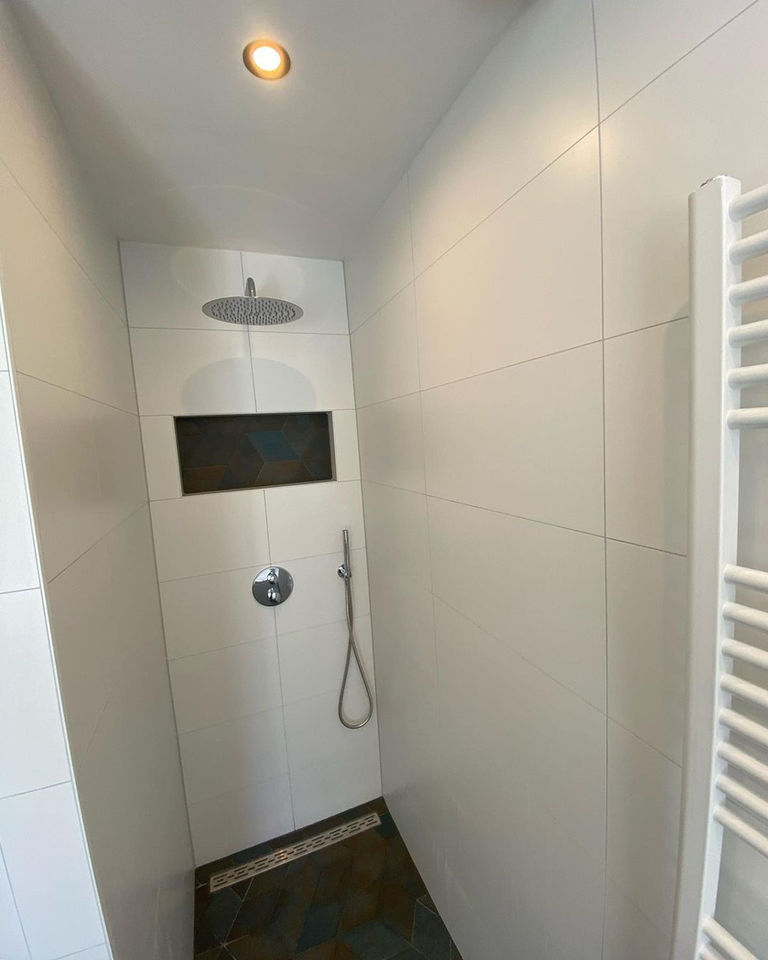 De vloertegel zit ook achter in de nis