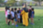 A group of children is gathered around outside at a Harry Potter theme party ready to play Quidditch.