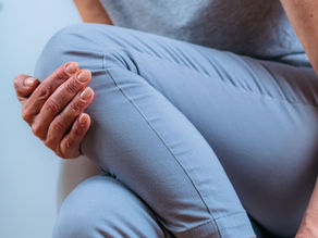 Woman over 50 holding her knee due to joint pain that moves around during perimenopause