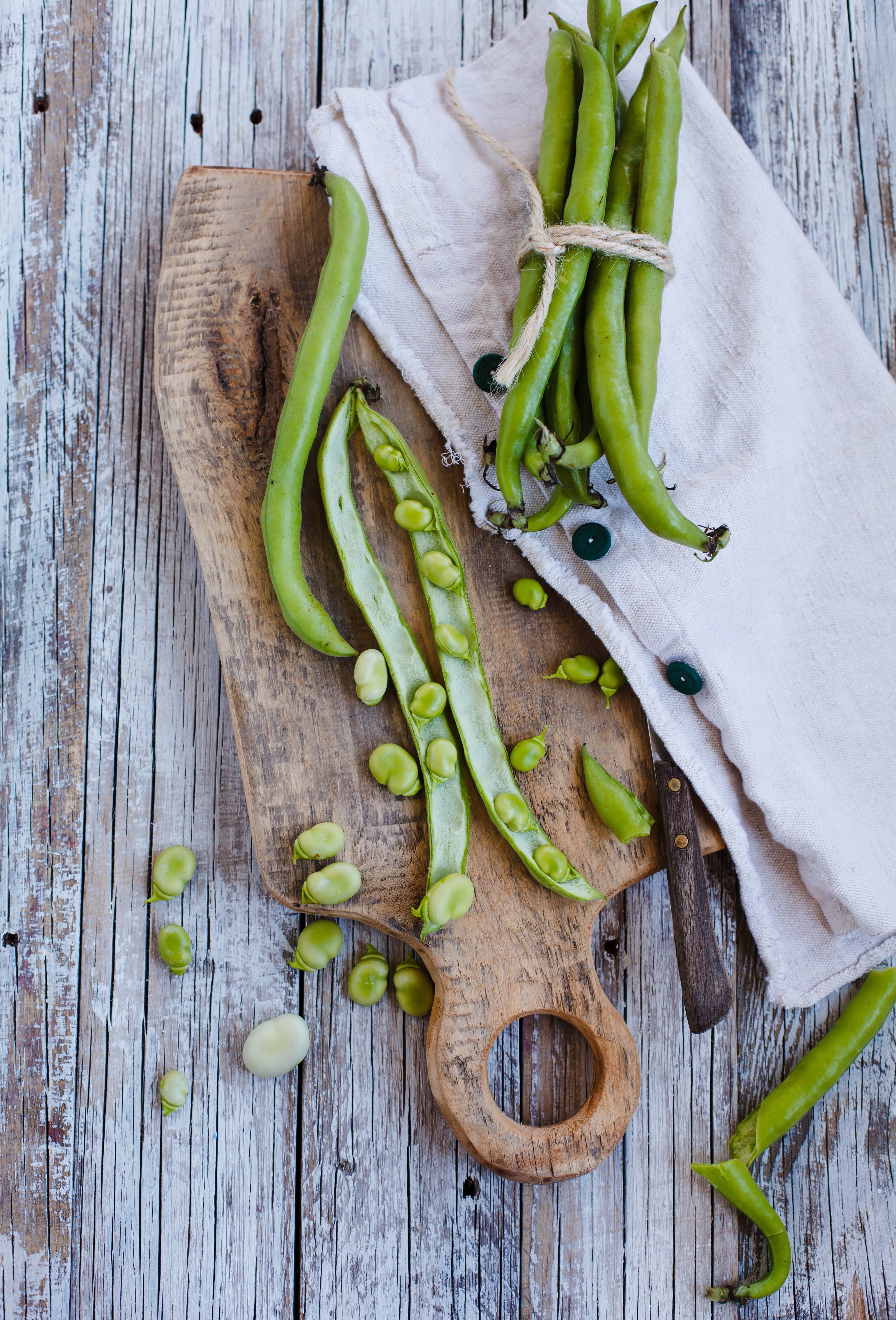 A rustic chopping board with broad beans. 