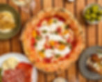 external restaurant table with pizza in themiddle with sharing plates around the outside