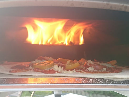Pizza cooking under a flame