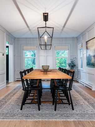 Light-filled dining room with custom white millwork, wood table and black pendant