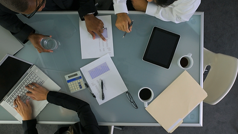 Picture of business meeting table with people holding business aparatus