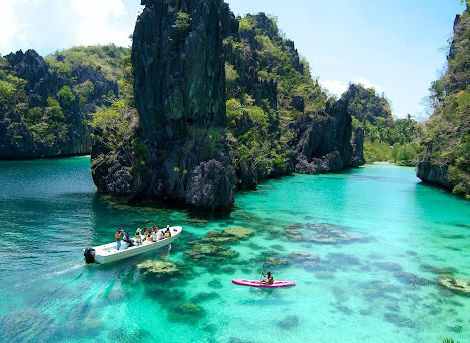 Students canoeing through clear blue waters and limestone cliffs during MD study abroad in the Philippines
