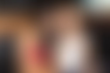 Two Filipina bar girls in black bikinis pose with arms around each other, smiling in a dimly lit room with festive string lights in the background.