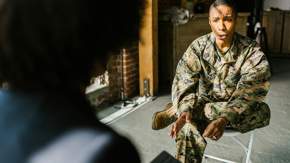 A soldier in military uniform during a therapy session indoors, discussing with a counselor.