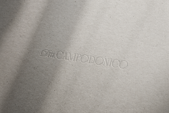 Detalle en relieve seco con el nombre Dra. Campodónico, propuesta de branding sobrio y profesional sobre papel texturado.