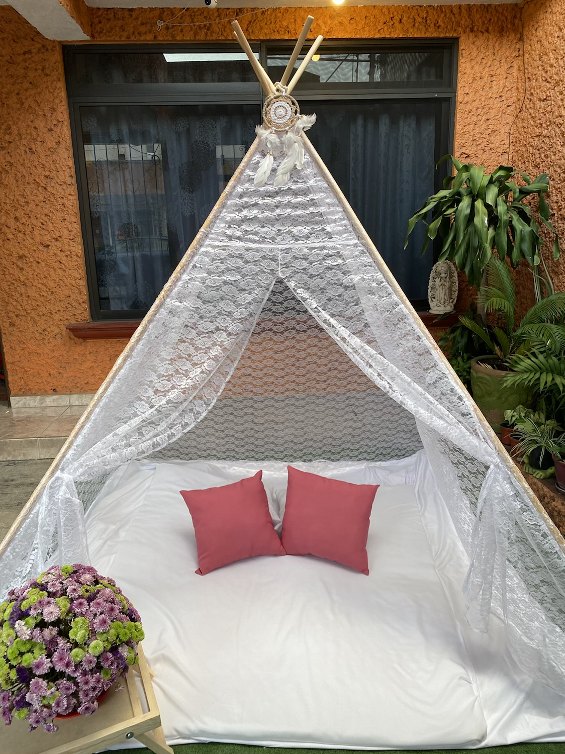 Cama tipi decorada con cojines rojos y flores; Puff redondos para Picnic niños.