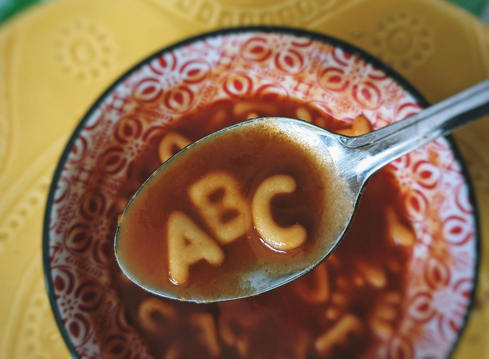 Spagetti shaped in alphabet letters, A, B and C in tomato sauce on a silver spoon