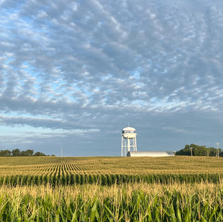 white water tower, field of corn, blue sky with clouds