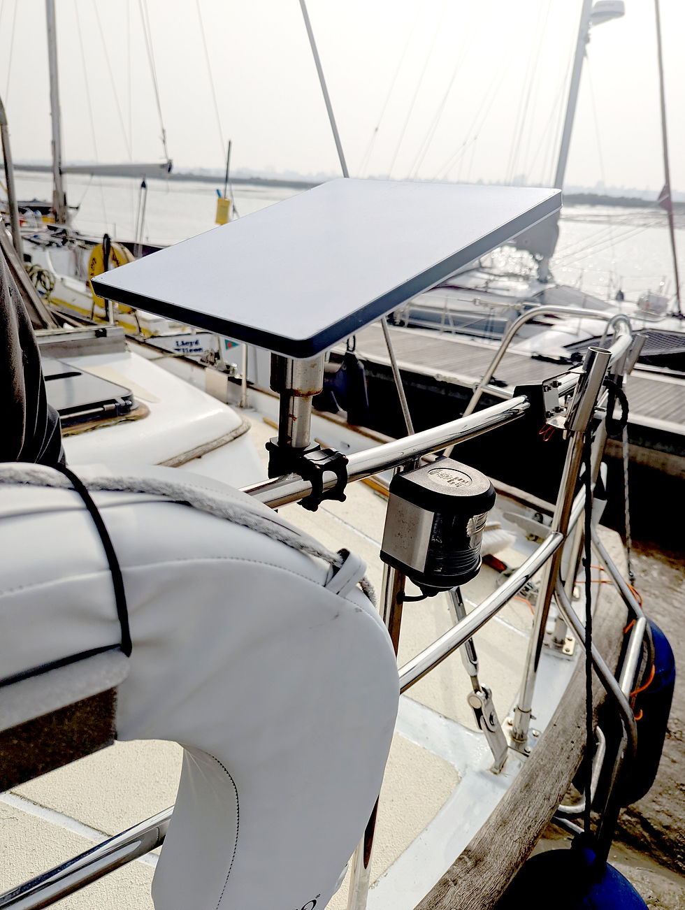 Starlink mounted on a boat's rail, overlooking a marina with sailboats. Bright, clear sky and calm water convey a serene mood.