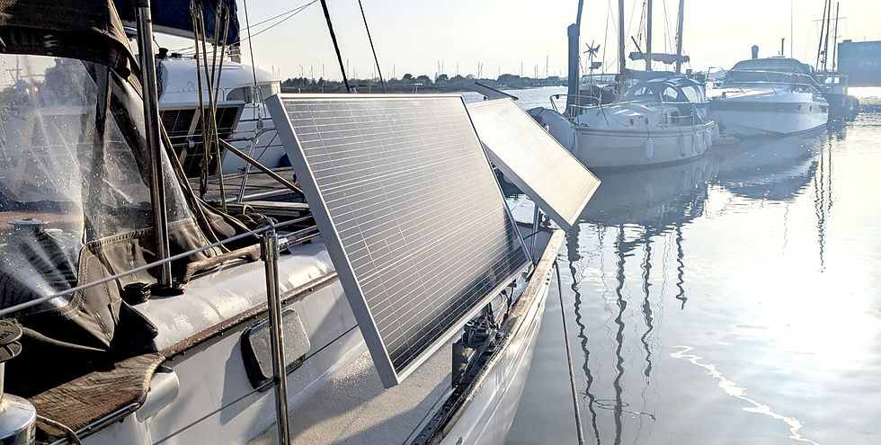 Solar panels on a boat deck reflecting sunlight by a marina. Other boats and calm water in the background under a clear sky.