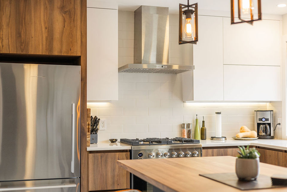 Cuisine contemporaine avec armoires bois et blanches, hotte en inox et électroménagers encastrés, Projet Montligeon
