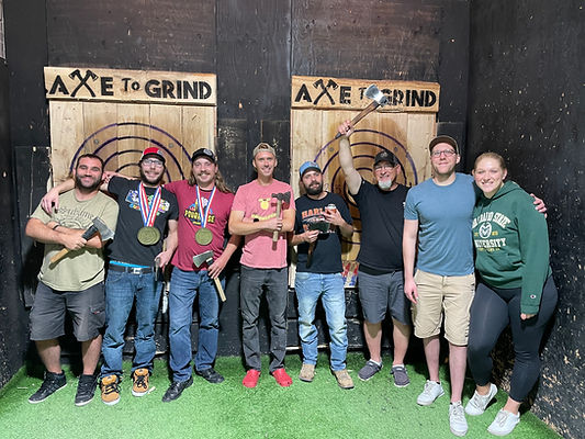 A group of people at an axe throwing range.