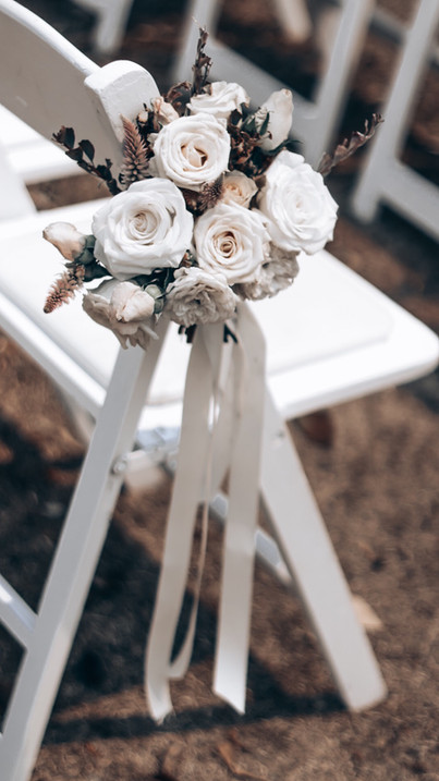 white posies of flowers tied to chairs