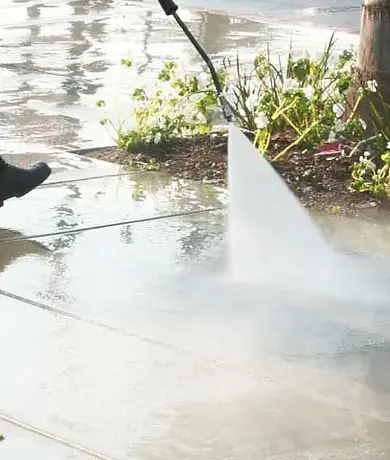 Power Pressure washing using powerful pressure to clean surface - concrete, plants, tree, and boots