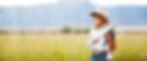 Boy in cowboy hat holding American flag in a grassy field