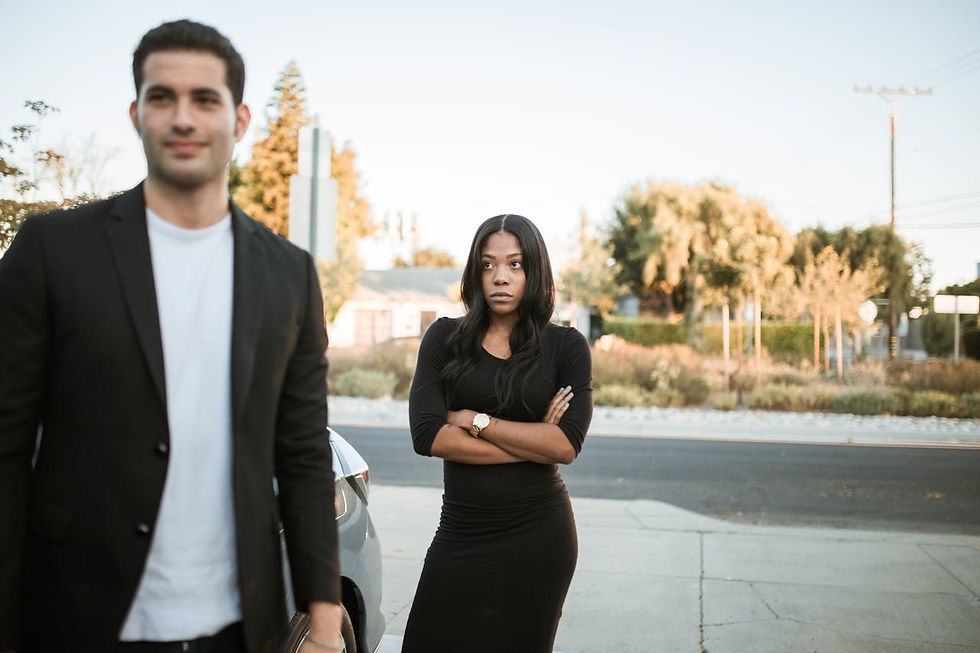 An upset woman standing with arms crossed while her partner walks away smiling, highlighting emotional imbalance and unresolved jealousy in an open relationship.