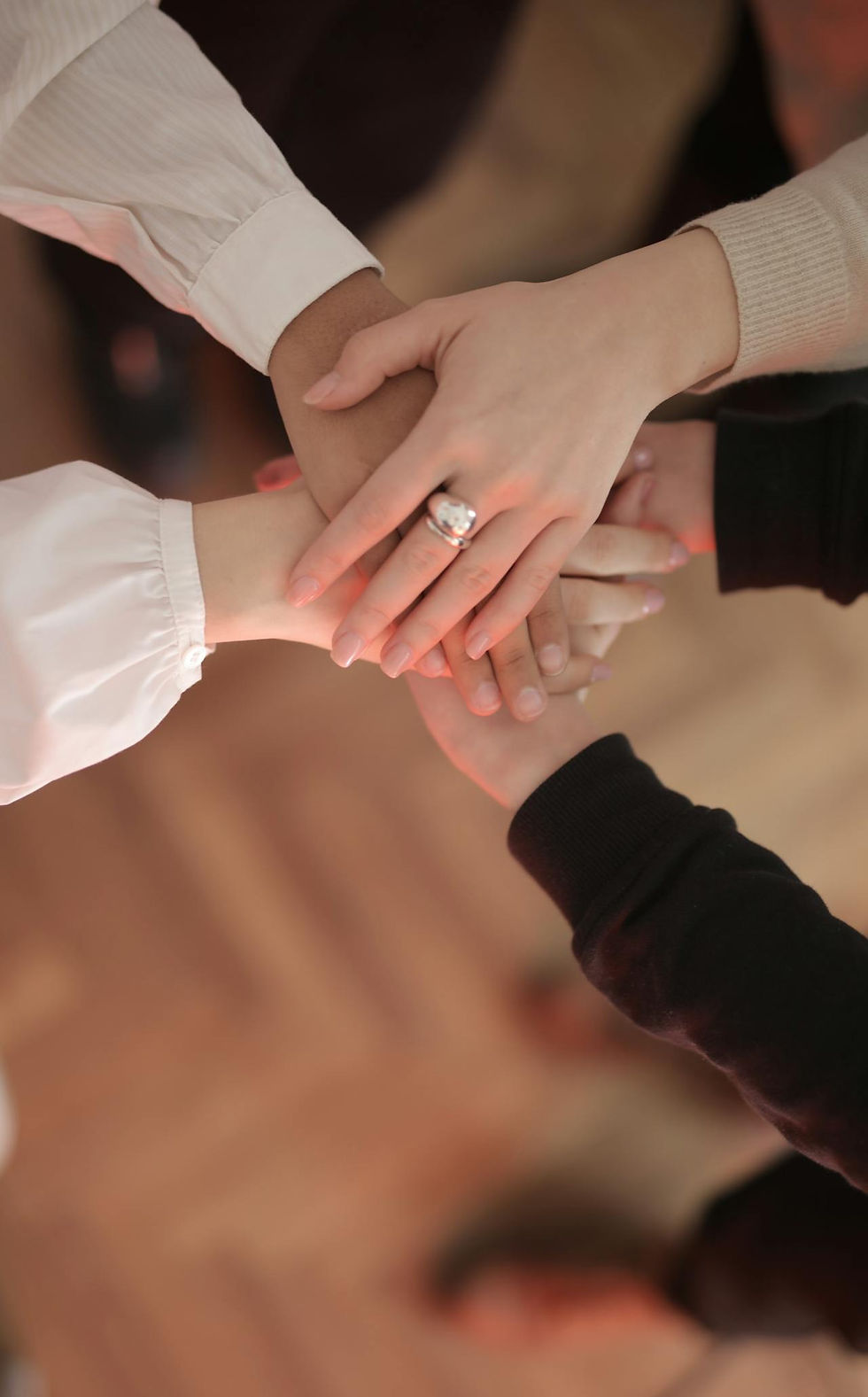A group of diverse hands stacked together in unity, representing mutual support, community, and trust in ethical non-monogamy and open relationships.