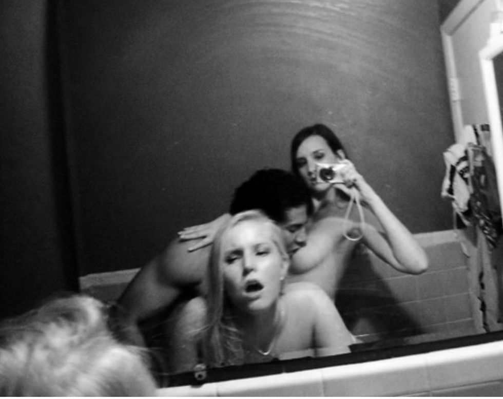 Sensual couple exploring mirror sex together in dim lighting