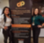 Two women standing beside a Rise Advocates women’s empowerment banner at a leadership and advocacy event.