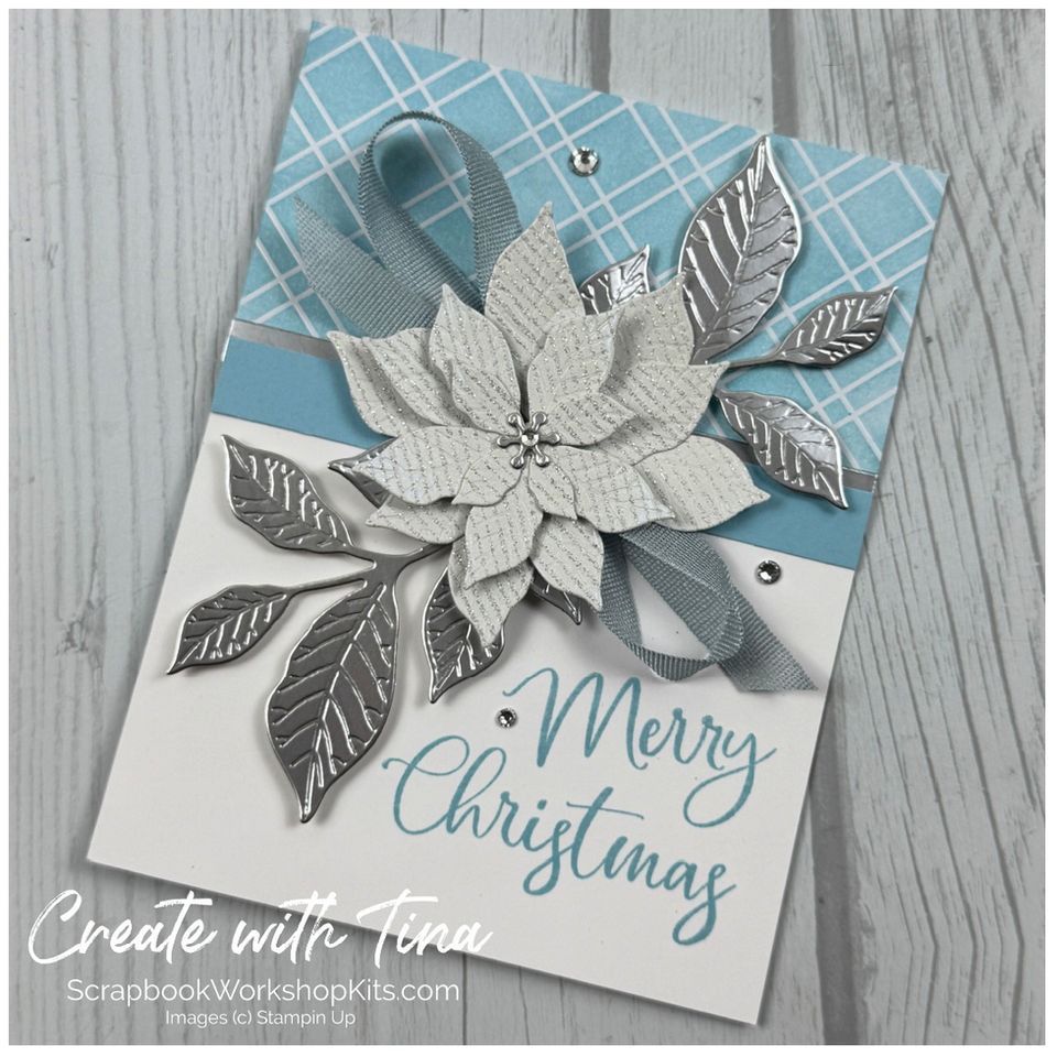Elegant Christmas card with a white shimmering poinsettia, silver foil foliage and blue plaid paper.