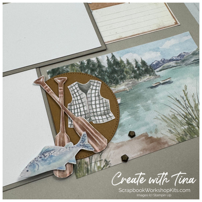 Close-up of outdoor scrapbook embellishments featuring lake scenery, paddles, fishing accents, and nature-inspired details fr