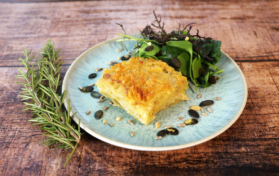 veganes Kartoffelgratin auf Teller mit Salat