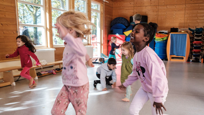 Kinder laufen, springen, bewegen sich durch den Raum. 
