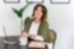 Image of Wellness Creative Owner Renee sitting at a round black table holding a cup of coffee
