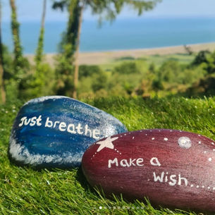 Two stones with the messages just breathe and make a wish with the sea in the background