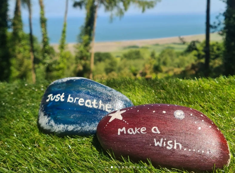 Two stones with the messages just breathe and make a wish with the sea in the background