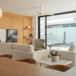 Open-plan mid-century living room with oak paneling, white sofas and pool views. Villa Verdealto, interior design by Noogar, Fuerteventura