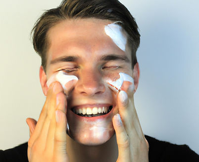 a young man smiling and washing his face with a foamy face cleanser.jpg