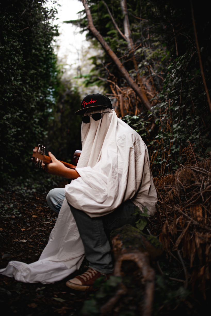 Sheet ghost playing guitar in the woods