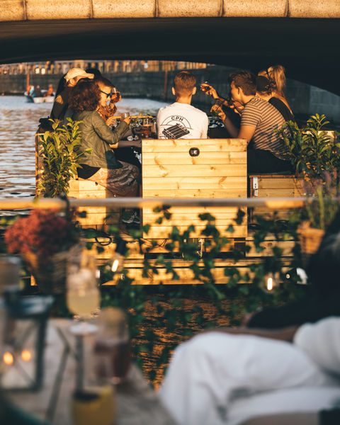 to green raft tømmerflåder med planter i hegnet sejler bag ved hinanden under en bro i Københavns havn 