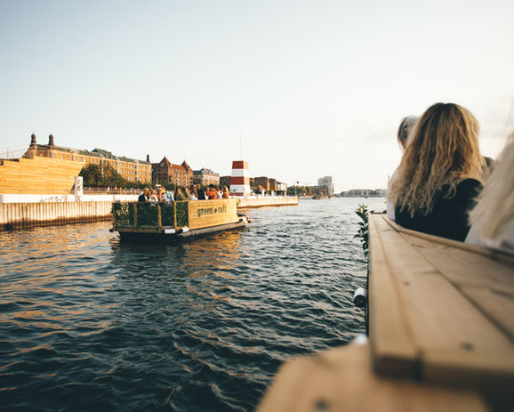 en green raft tømmerflåde sejler forbi en badezone i Københavns havn