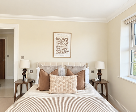 Bedroom styled with neutral bedding, textured cushions, bedside lamps and framed artwork