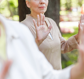 Qigong Class outdoors showing a woman holding up her hands